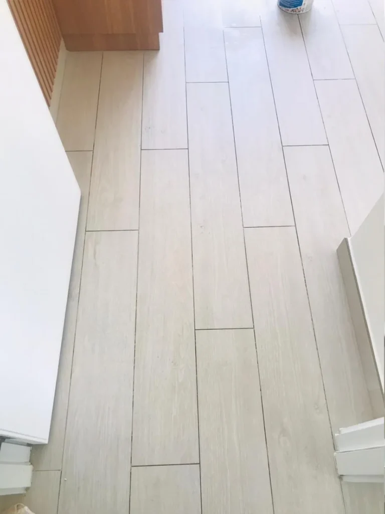 Light wood-look porcelain tile flooring with professionally installed clean grout lines by Grout Prince in Dubai